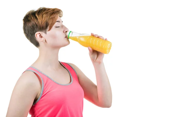 健康的生活方式，健康的饮食。年轻的女孩从孤立的白色背景上的一瓶喝桔子汁。水平框架 — 图库照片
