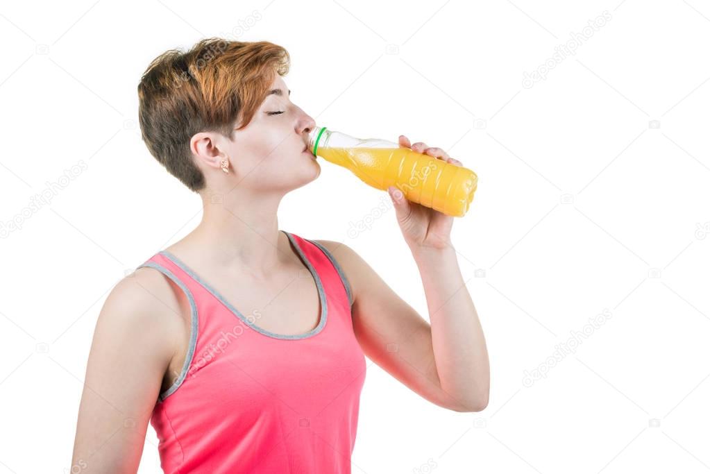 Healthy lifestyle, healthy eating. Young girl drinks orange juice from a bottle, isolated on white background. Horizontal frame