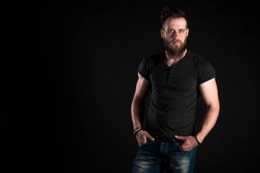 Sakallı karizmatik ve şık bir adam siyah bir izole arka plan üzerinde tam uzunlukta duruyor. Yatay Çerçeve