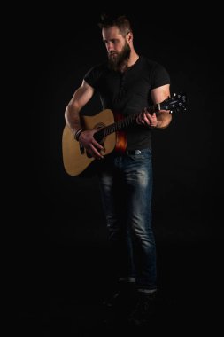 Bir sakallı bir karizmatik ve şık adam tam uzunlukta standları ve akustik gitar, siyah bir izole arka planda çalar. Dikey Çerçeve