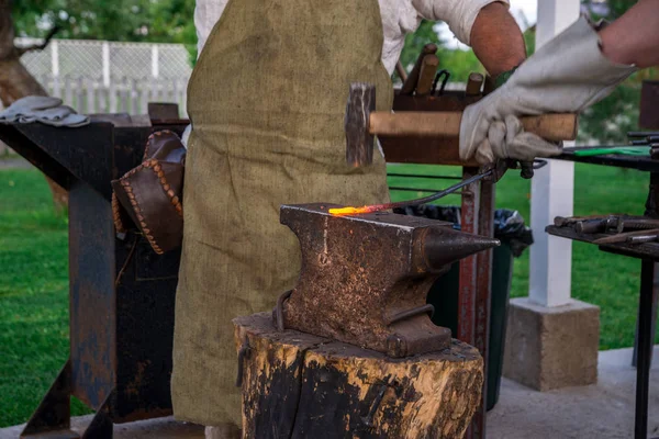 Zwei Schmied in der Nähe des Ambosses. Man hackt ein Hufeisen mit einem Schinken — Stockfoto