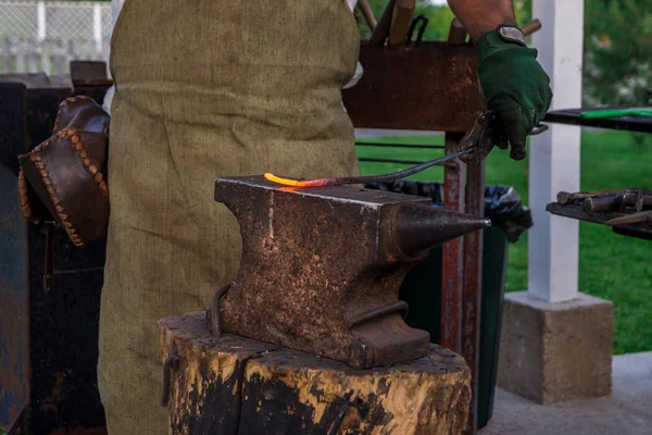 The smith holds a metal bar heated to melting on the anvil, befo