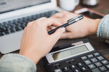 Sabah iş kadını. Dizüstü bilgisayar, telefon ve kadın elinde hesap makinesi. Yatay Çerçeve