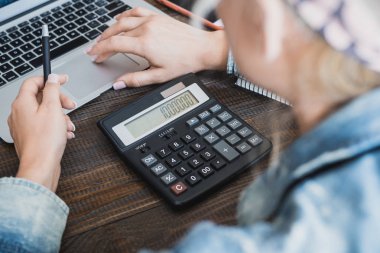 Sabah iş kadını. Dizüstü bilgisayar, telefon ve kadın elinde hesap makinesi. Yatay Çerçeve