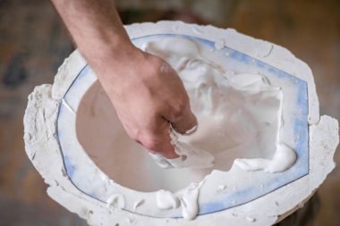 Heykeltıraşın elinde beyaz sıvı kalıp içine doldurun. Yatay Çerçeve