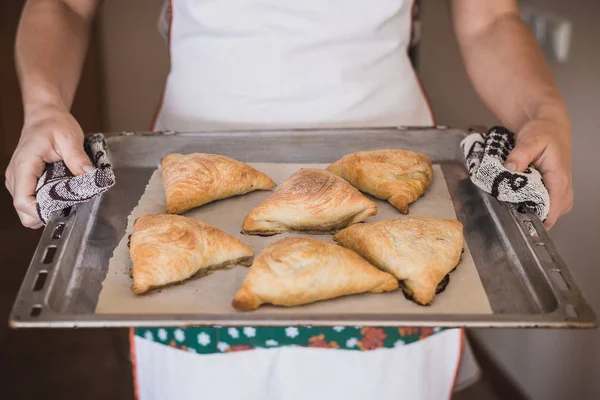 Cocina nacional uzbeka. Samsa en una bandeja, en manos femeninas. Marco horizontal — Foto de Stock