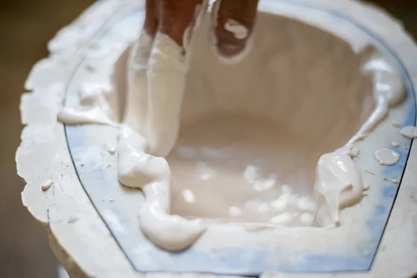 As mãos do escultor enchem o líquido branco no molde. Quadro horizontal — Fotografia de Stock