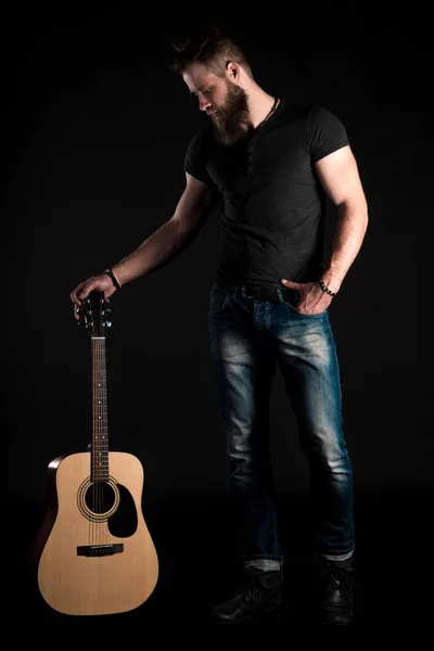 A karizmatikus és elegáns férfi szakáll áll teljes hosszúságú elszigetelt fekete alapon akusztikus gitár. — Stock Fotó