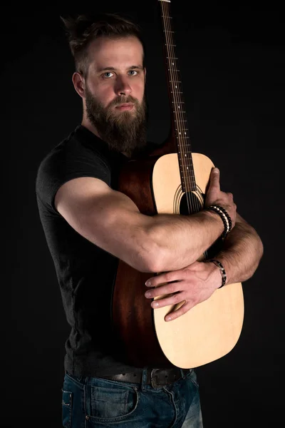 孤立した黒地にアコースティック ギターとひげを持つカリスマ的でスタイリッシュな男立つフルレングス. — ストック写真