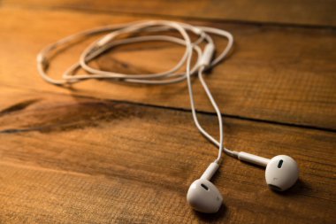 Ahşap izole arka plan üzerinde beyaz küçük kulaklıklar. Yatay Çerçeve