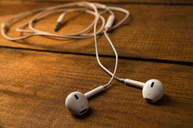 Ahşap izole arka plan üzerinde beyaz küçük kulaklıklar. Yatay Çerçeve