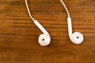 Ahşap izole arka plan üzerinde beyaz küçük kulaklıklar. Yatay Çerçeve