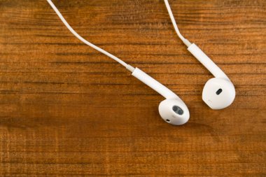 Ahşap izole arka plan üzerinde beyaz küçük kulaklıklar. Yatay Çerçeve