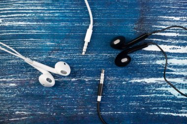 Küçük beyaz ve siyah kulaklık bir mavi kot arka plan üzerinde yalan. Yatay Çerçeve