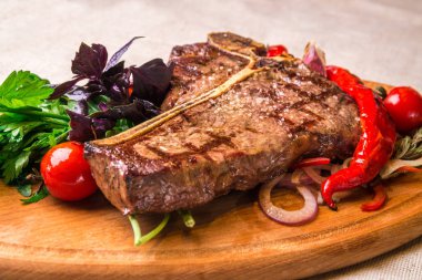 İştah açıcı biftek bir kemik, domates, biber, bir ahşap tahta üzerinde. Yatay Çerçeve