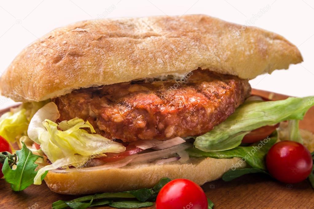 A sandwich with fried chops, herbs, tomatoes, peppers. Horizontal frame