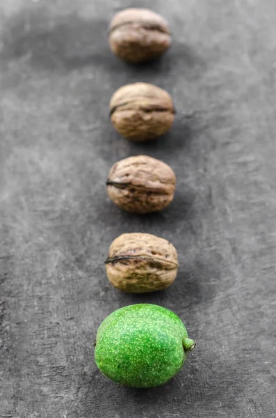 Cuatro nueces peladas texturizadas y una verde mienten una línea — Foto de Stock