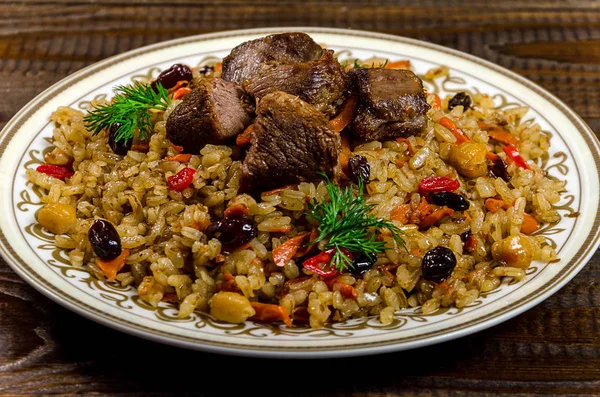 Uzbek national pilaf dish on a dark wooden background — Stock Image Uzbek national pilaf dish on a dark wooden background Royalty Free Stock Images