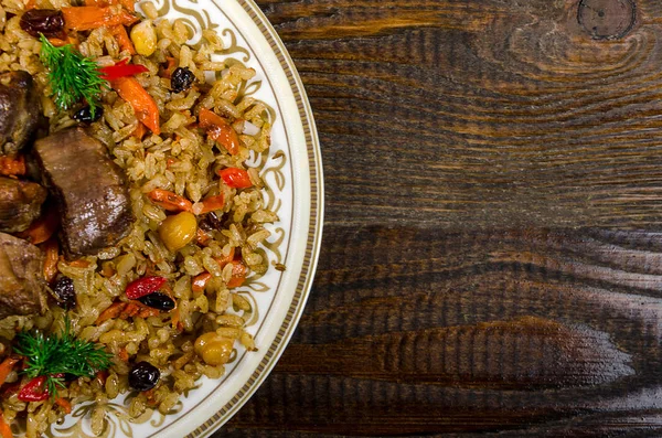 Uzbek national pilaf dish on a dark wooden background — Stock Image Uzbek national pilaf dish on a dark wooden background Royalty Free Stock Photos