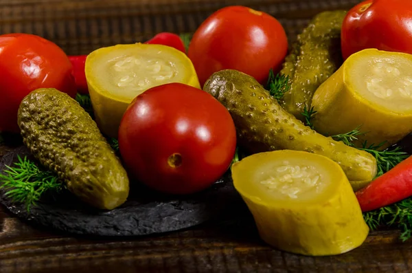Pickles: cucumber tomatoes, zucchini and herbs scattered on a wooden background — Stock Photo, Image