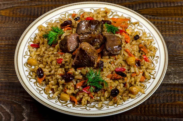 Uzbek national pilaf dish on a dark wooden background — Stock Image Uzbek national pilaf dish on a dark wooden background Stock Image