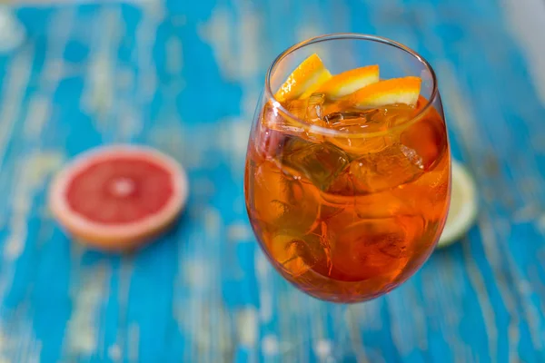 Um copo com uma bebida e laranja em um fundo azul — Fotografia de Stock