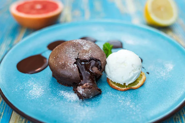 Torta al cioccolato con una pallina di gelato bianco su un piatto blu — Foto Stock