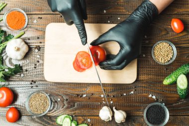 kadınların elleri kesilmiş yalan biber yanındaki bir domates, otlar, salatalık ve baharatlar