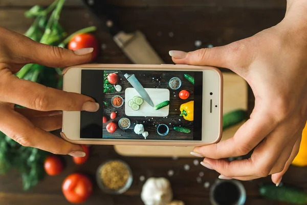 women\'s hands with a phone take pictures of vegetables