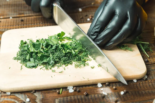 women\'s hands cut herbs, next to them are tomatoes, paprika, cucumbers