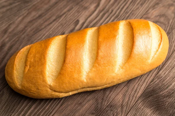 Loaf of bread on a brown wooden background — Stock Photo, Image