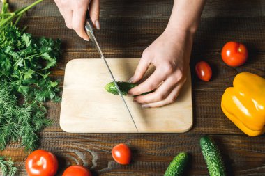 kadınların elleri bir salatalık, domates, yakın kırmızı biber kesmek