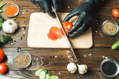 kadınların elleri kesilmiş yalan biber yanındaki bir domates, otlar, salatalık ve baharatlar