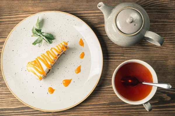 Pezzo di torta leggera e tè su uno sfondo di legno — Foto Stock