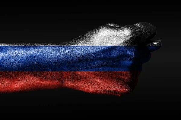 Eine Hand mit einer bemalten russischen Flagge zeigt eine Feige, ein Zeichen von Aggression, Uneinigkeit, Streit auf dunklem Hintergrund. — Stockfoto