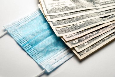 Yüzündeki tıbbi bandaj bir paket doların yanında duruyor. Doktora rüşvet ver, Coronavirus 'a karşı ilaç al..