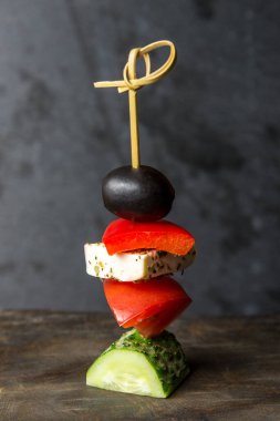 Gri arka planda küçük bir şişte lezzetli sebze kanepeleri..