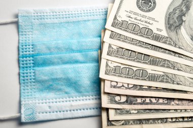 Yüzündeki tıbbi bandaj bir paket doların yanında duruyor. Doktora rüşvet ver, Coronavirus 'a karşı ilaç al..