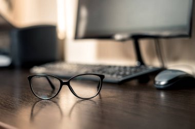 Çalışma alanı, bilgisayar ve bardaklar masada..