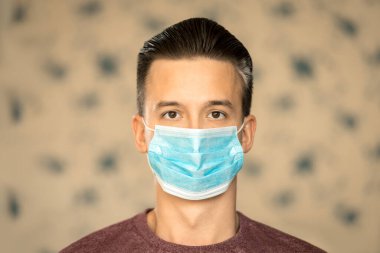 Koronavirüs ve güvenlik teması. Virüsten gelen mavi maskeli genç bir adam..