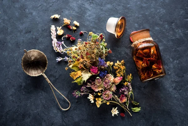 Herbs and flowers for herbal healing tea on black concrete background, top view