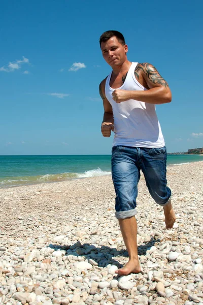 Der Mann läuft den Strand entlang — Stockfoto
