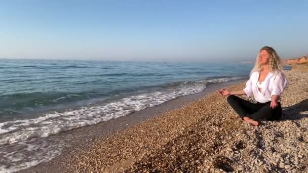 Bella Donna Bionda Seduta Meditando Sulla Spiaggia Vicino Alle Onde — Video Stock