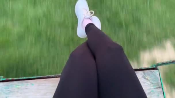 Femme sur une balançoire à la plage au coucher du soleil. Vue à la première personne .