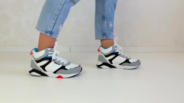 穿牛仔裤和运动鞋的女人的细腿 搬家时 运动鞋会换成新运动鞋 许多不同颜色的运动鞋 — 图库视频影像