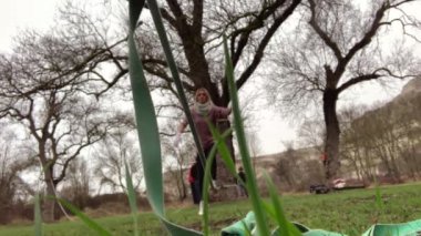 Beautiful slender blond woman learns to walk on the slackline. The sling is stretched in the forest, autumn is cold.
