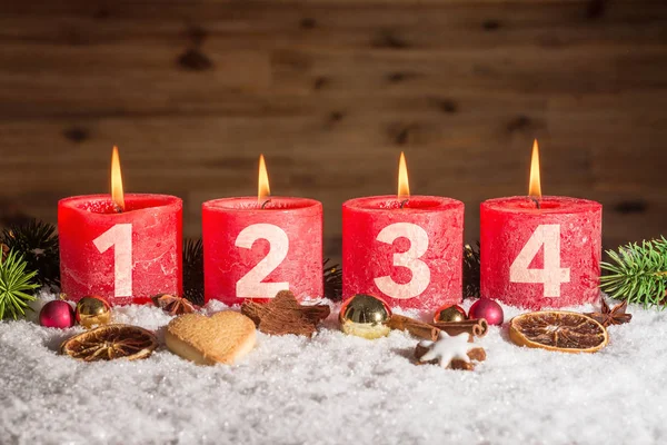 Four advent candles lit in snow