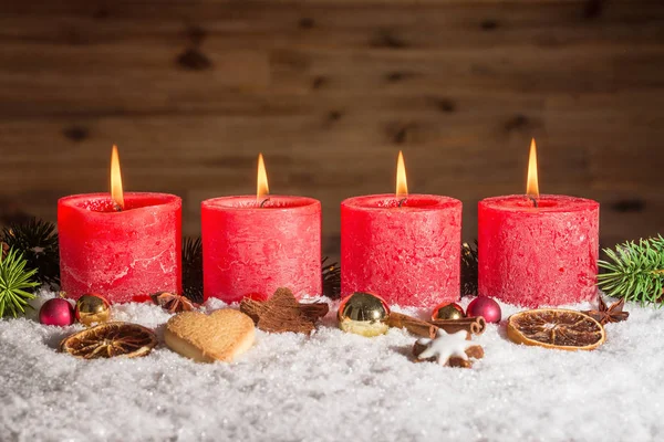 Quatro velas de advento acesas na neve — Fotografia de Stock