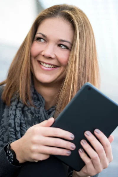 Junge Frau lächelt mit Tablette in der Hand — Stockfoto