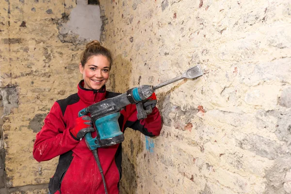 Ambitious craftswoman with caulking hammer in front of brick wal — Stock Photo, Image